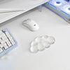 A white ergonomic cloud wrist rest is shown next to a white computer mouse and a keyboard on a white desk surface.