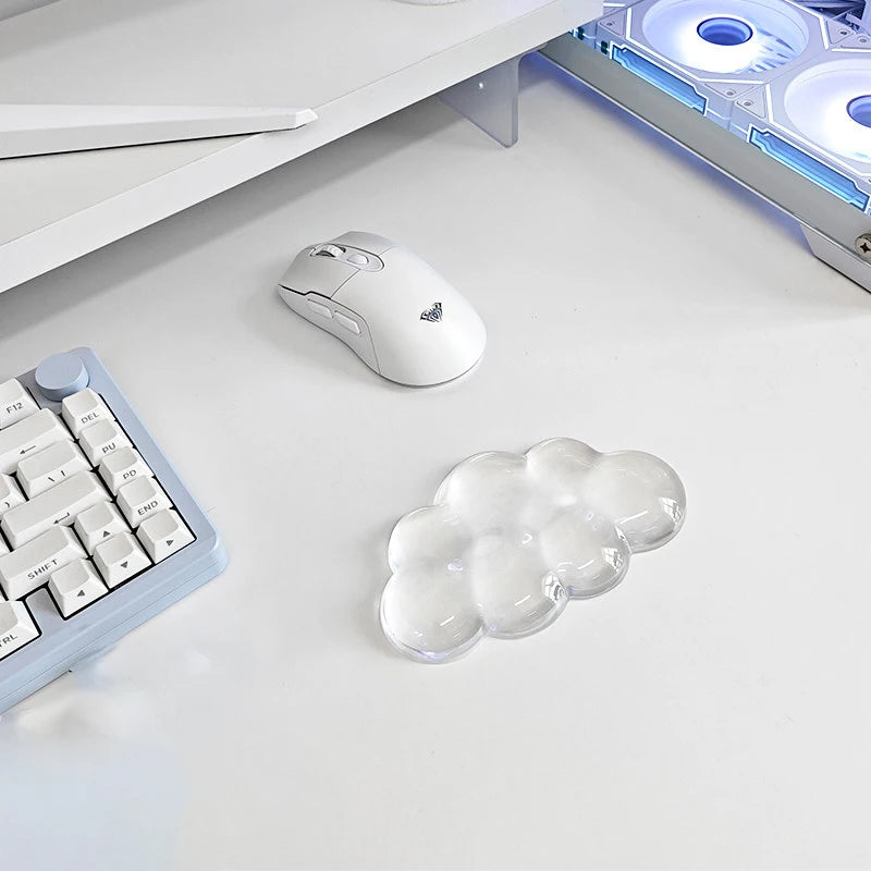 A white ergonomic cloud wrist rest is shown next to a white computer mouse and a keyboard on a white desk surface.