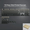مجموعة من 133 غطاء مفاتيح (keycaps) من PBT متدرج الطباعة الجانبية لللوحات الميكانيكية معروضة على سطح رمادي داكن.