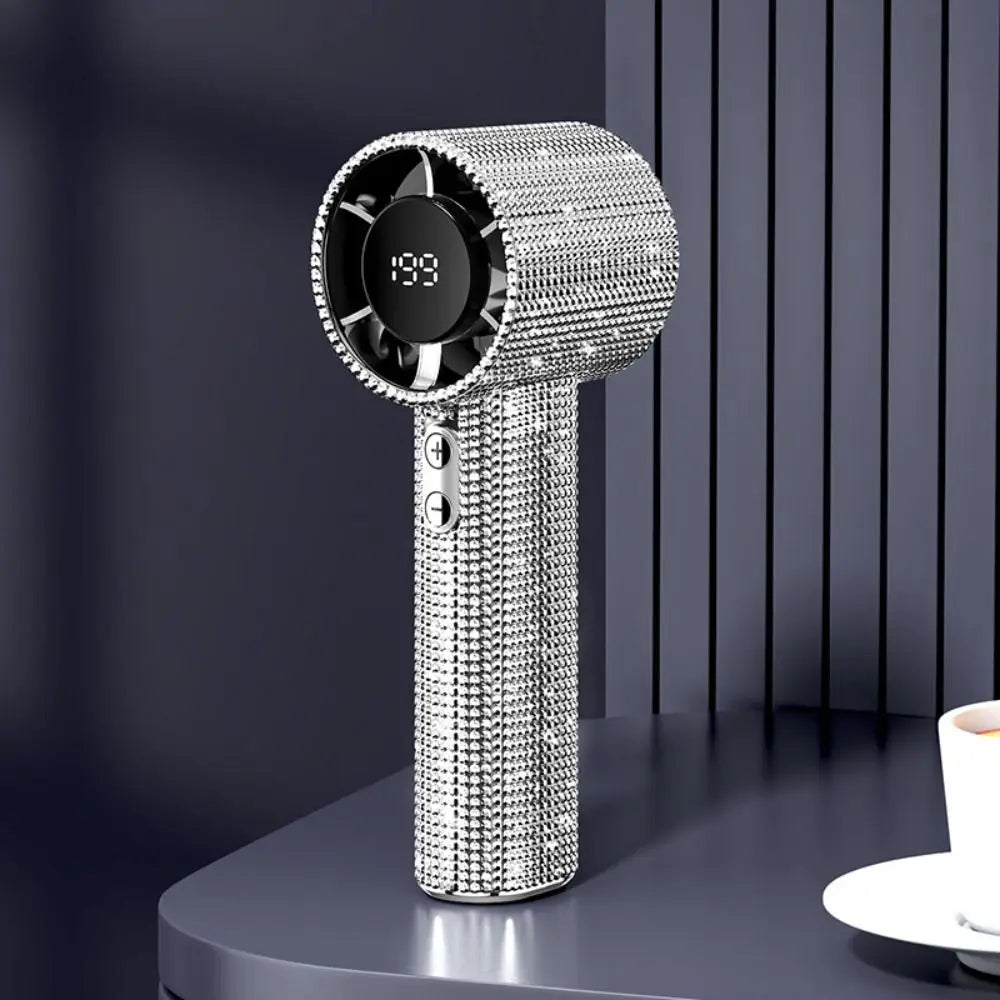 A silver mini portable LED turbine fan with a circular grille and digital display is shown on a dark surface.
