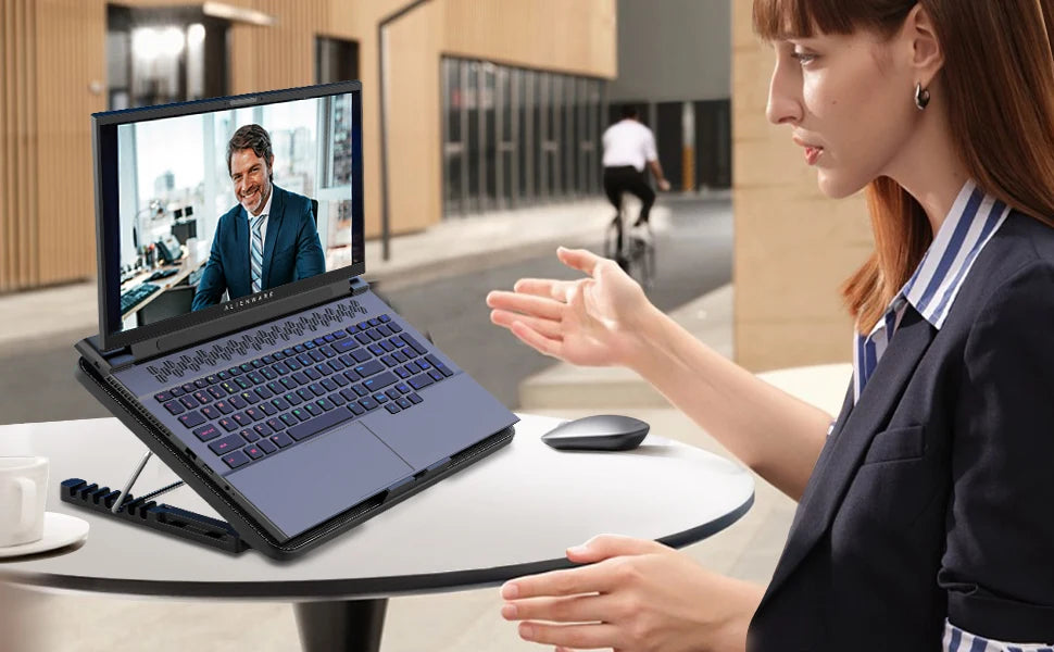 A woman is using an adjustable laptop cooling pad with a multi-fan technology while working on a laptop.