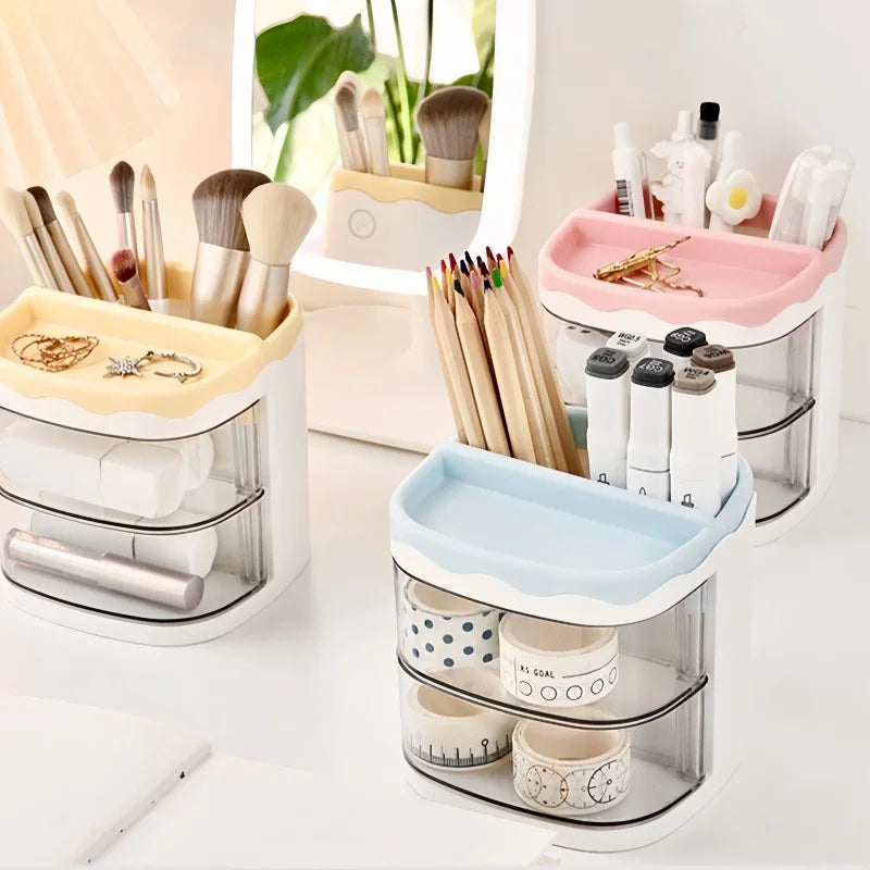 A set of clear acrylic desktop pen holders with various brush and cosmetic tools in pink, beige, and blue colors.
