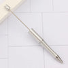 A silver DIY beadable pen with a pointed tip rests on a white tiled surface.