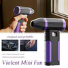 Un mini ventilador violento morado y negro sostenido por una mano, destacando su diseño compacto.