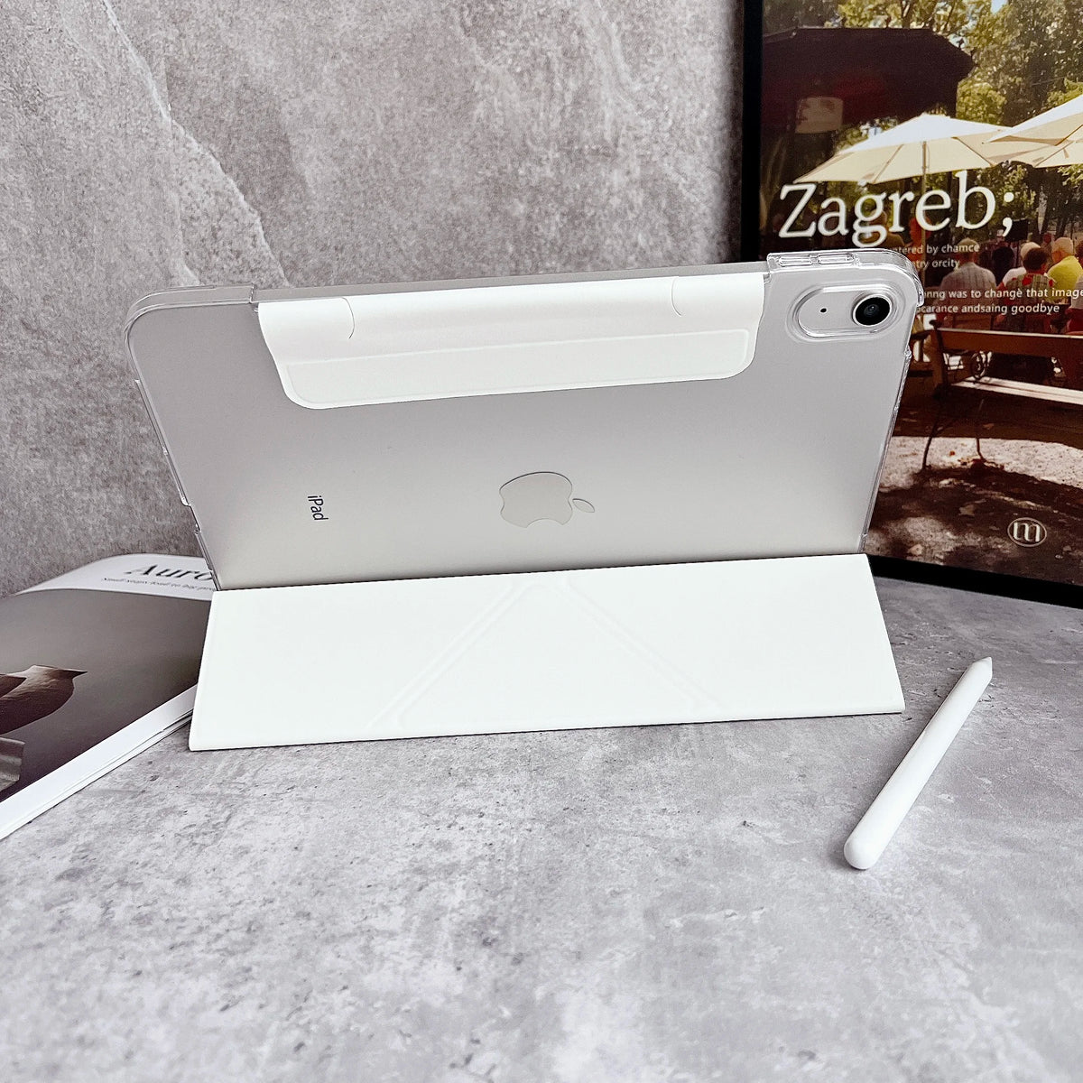 Un iPad blanco está apoyado en una funda protectora blanca sobre un fondo oscuro.