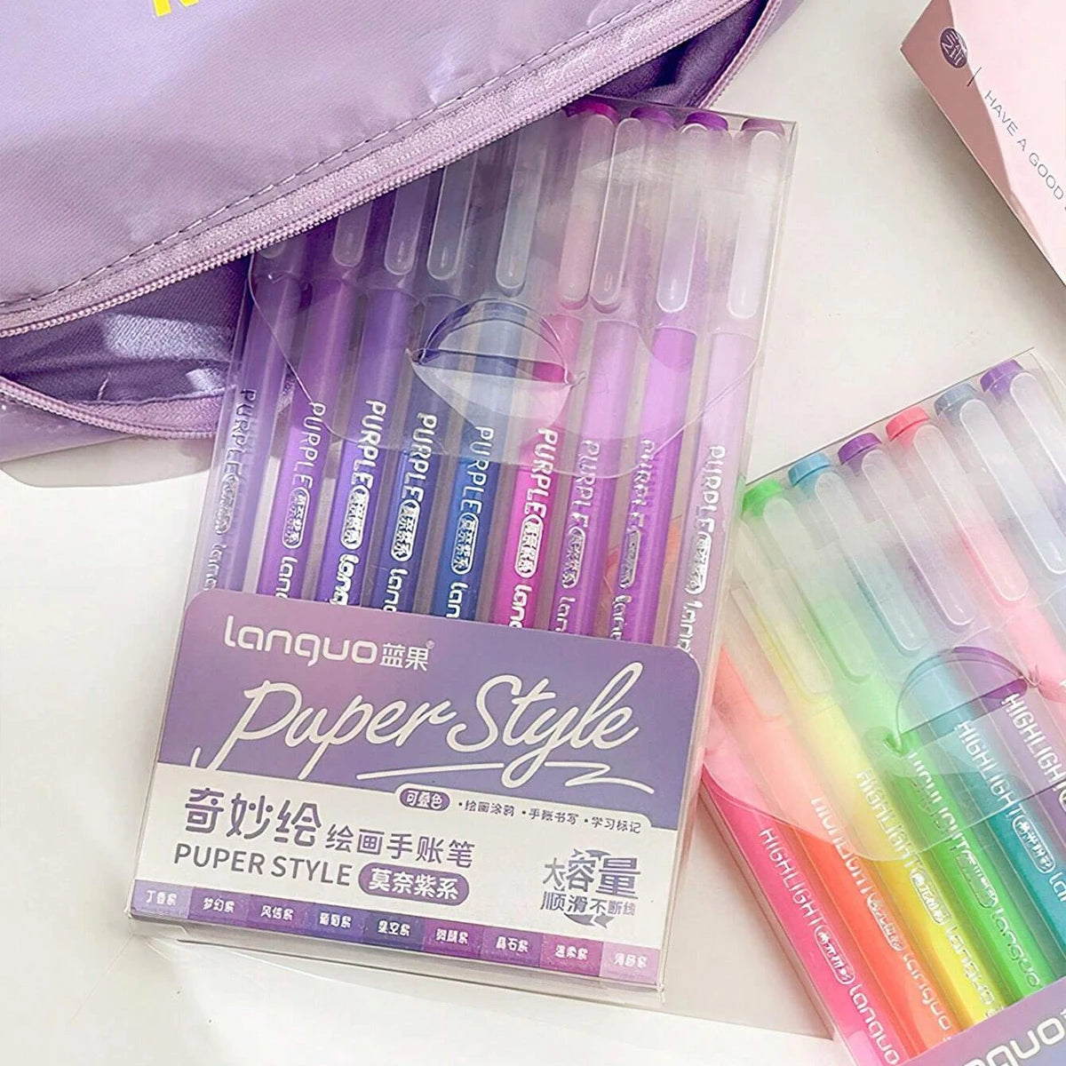 A set of multi-color gel pens in purple and green shades is displayed next to a purple pouch.