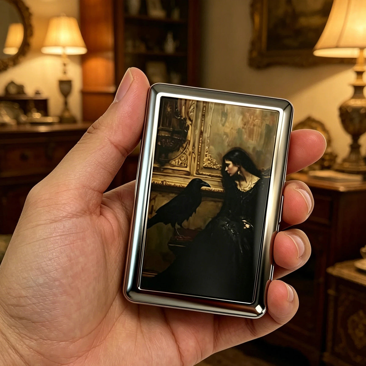 A hand holds a vintage stainless steel card and cash case featuring an antique painting of a bird.