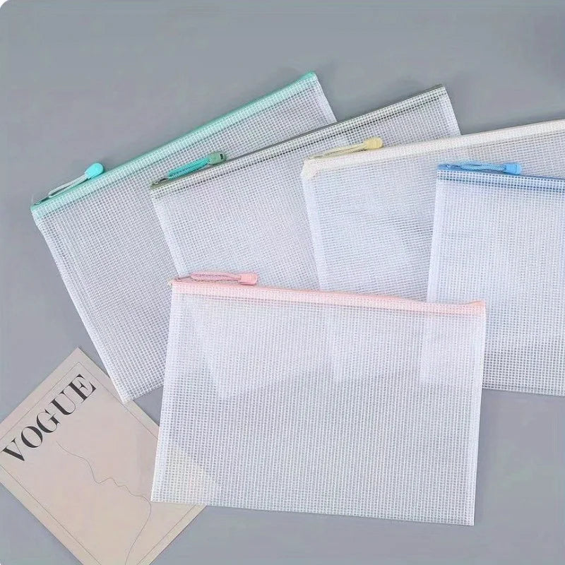 A collection of clear mesh zipper bags in white and pink are displayed on a gray surface.