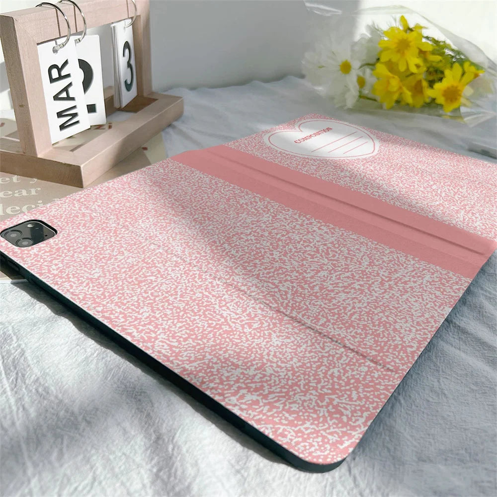 Pink composition book cover with a textured pattern and a pencil holder resting on a white sheet.