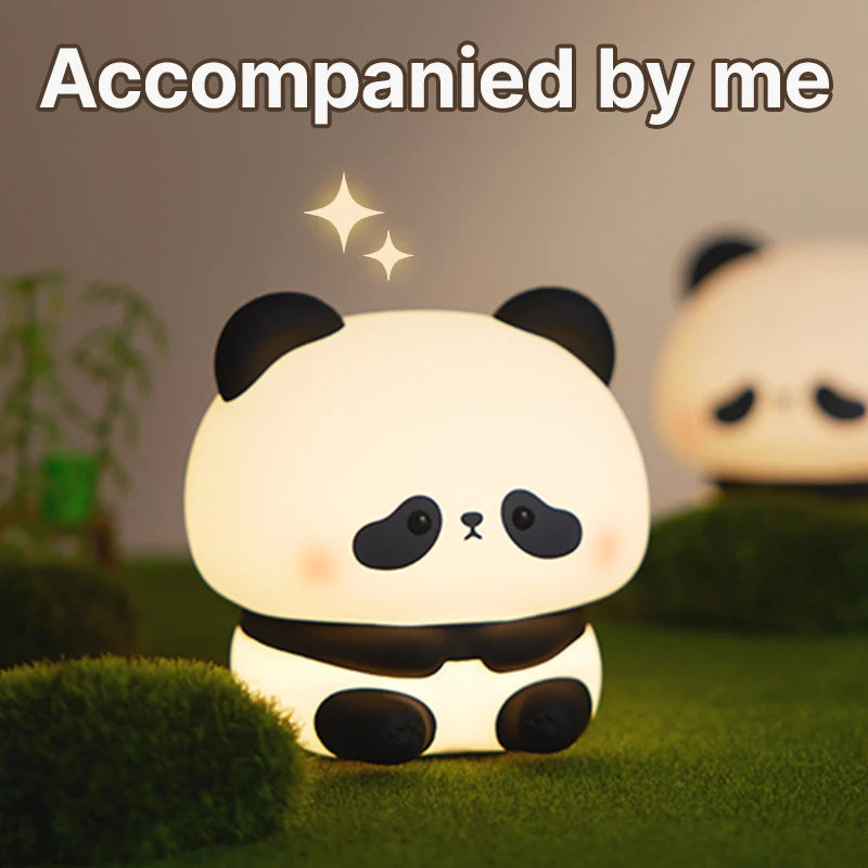 A cute white panda silicone night light with black accents is shown resting on green moss.