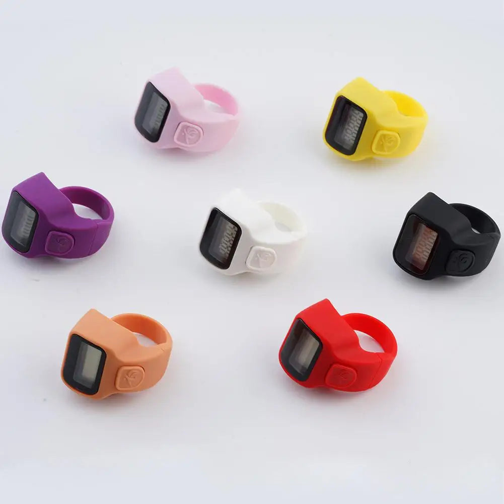 A collection of colorful thumb tally counters in various colors including pink, yellow, purple, white, black, and red.