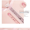 Pink plastic ruler with cat paw designs showing various measurements and scales.
