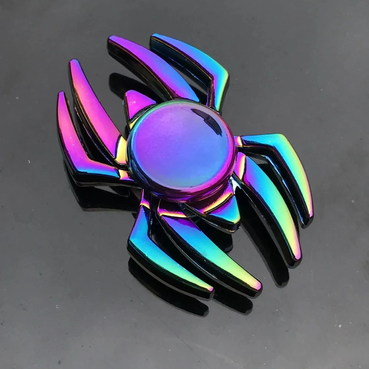 A rainbow metal fidget spinner with iridescent blades and a reflective center.