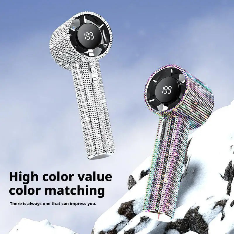 A silver handheld cooling fan with a black grille and iridescent color matching is shown against a snowy background.