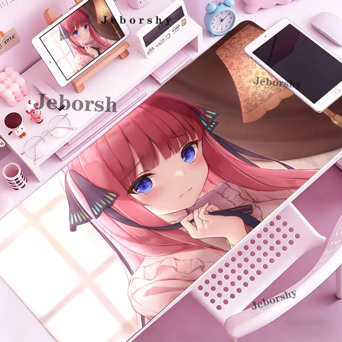 A close-up of a pink-haired anime girl resting on a purple desk mat with various accessories and a tablet.