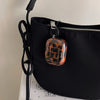 A black protective case for AirPods featuring a glossy tortoiseshell pattern.