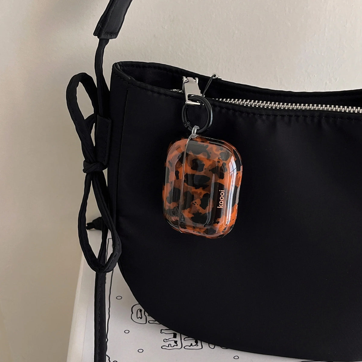 A black protective case for AirPods featuring a glossy tortoiseshell pattern.