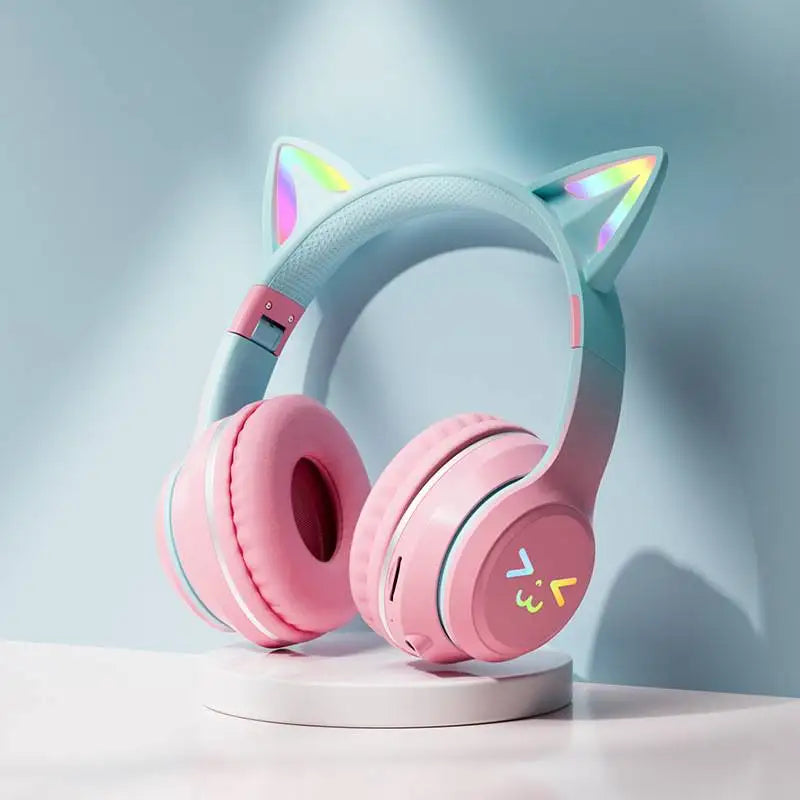 Light blue and pink gradient cat ear Bluetooth headphones resting on a white surface.