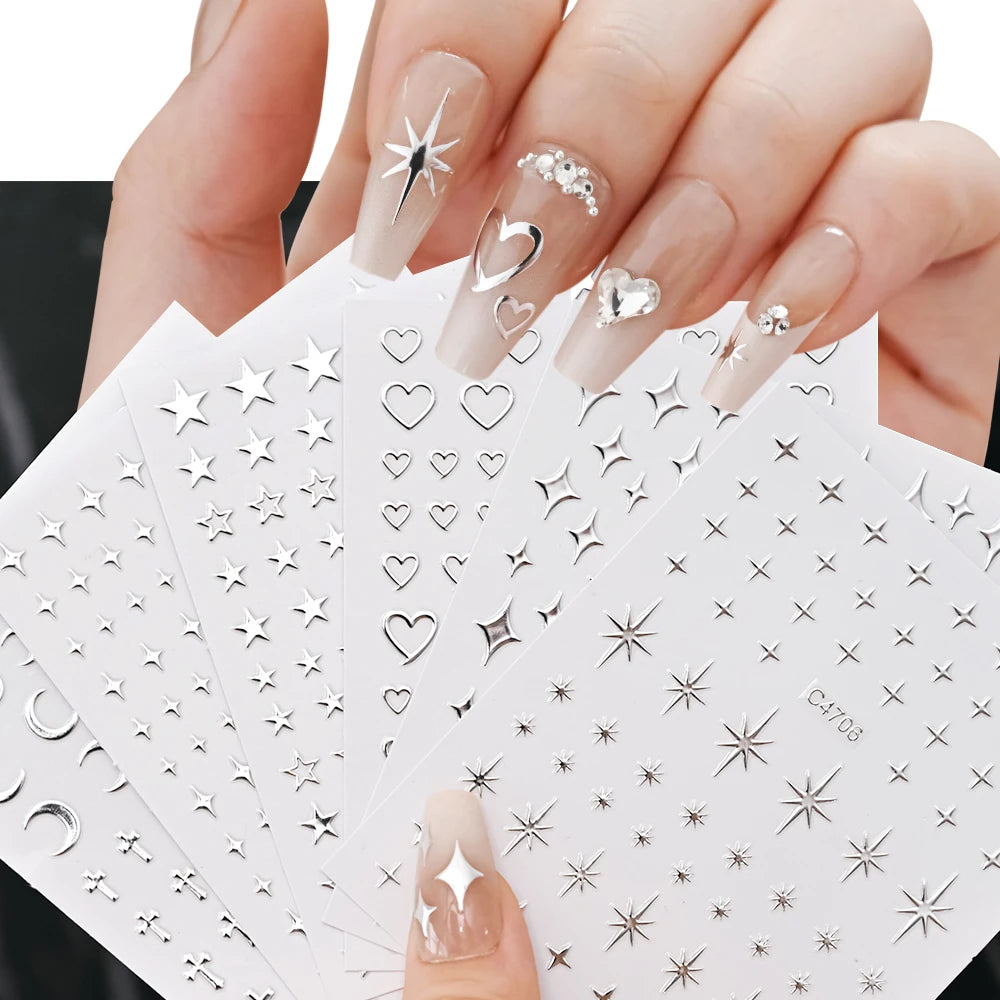 A hand holds a set of metallic 3D star nail art stickers on white tiles.