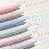 A collection of six pastel gel pens in pink, brown, blue, green, white, and purple are lined up on a sheet of paper.
