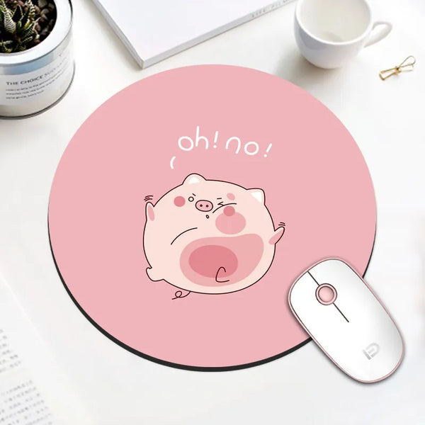 A pink cartoon pig face with an expression of surprise is printed on a round mouse pad next to a computer mouse.