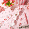 Pink adhesive thank you stickers arranged on a white grid with pink flowers and a pink pen.