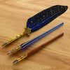 A luxury fountain pen set featuring a dark blue feather pen and a wooden pen with a gold nib, displayed on a wooden surface.
