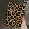 A close-up of a leopard print protective skin for an iPad case being held by a hand.