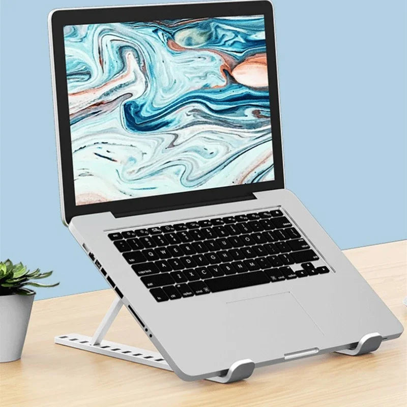 A silver laptop is resting on a foldable adjustable stand on a wooden surface.
