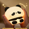 Hands hold a glowing panda silicone night light demonstrating its skin-friendly and soft features.