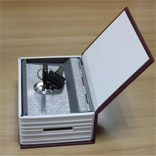 A classic book-shaped piggy bank with a lid open, showing a lock and key mechanism inside.