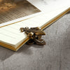 Two bronze iris-shaped metal binder clips resting on a lined paper inside a notebook.