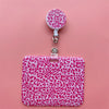 A pink leopard print retractable card holder clip with a white cap and clear plastic holder.