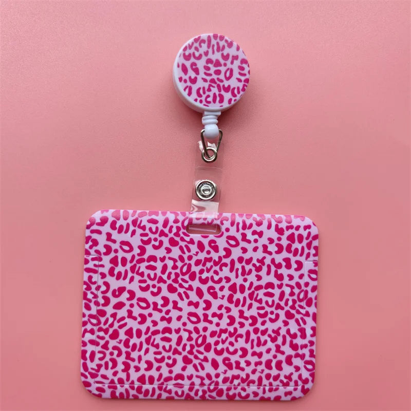 A pink leopard print retractable card holder clip with a white cap and clear plastic holder.
