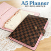 A pink A5 planner with a brown checkered cover and a leather binder shown on a wooden surface.