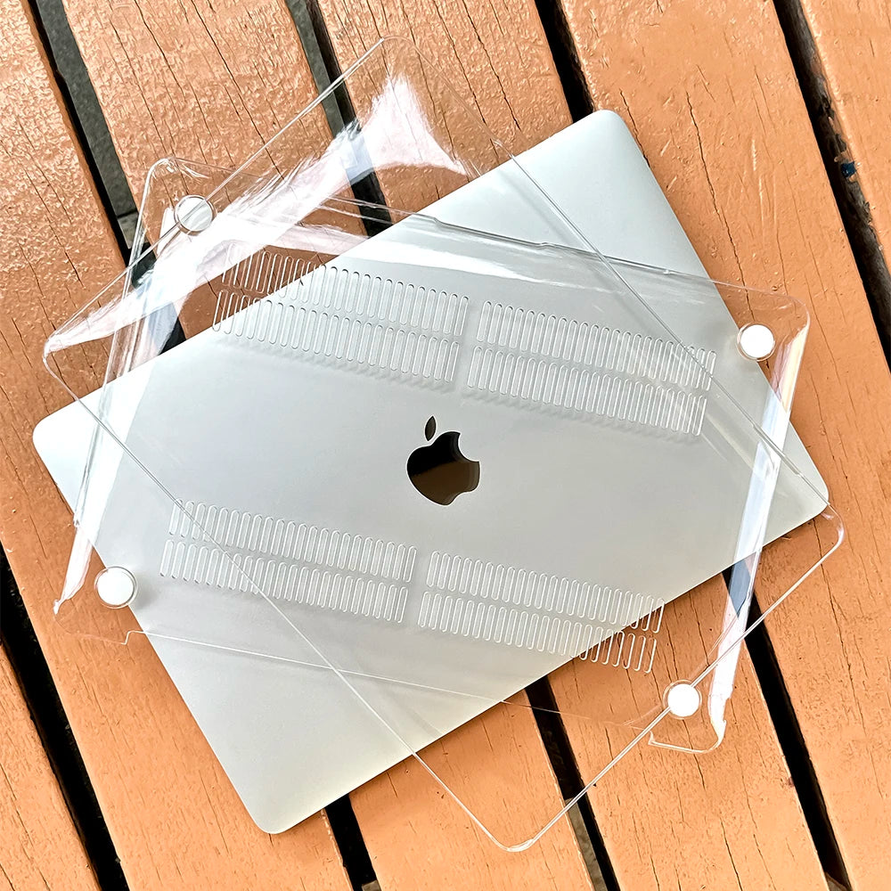 Eine klare Schutzhülle liegt auf einem silbernen MacBook Pro Laptop auf einer Holzoberfläche.