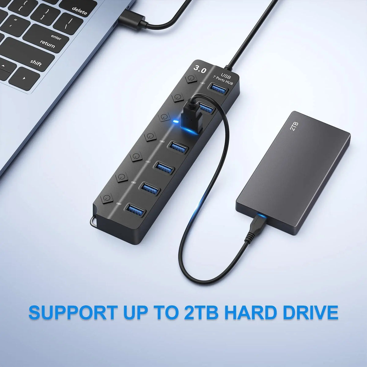 A black 7-port USB 3.0 hub extender with a cable connected, shown next to a laptop keyboard.