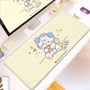 A light yellow cartoon illustration of a cat is printed on a gaming desk mat placed on a wooden desk.