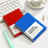 A blue spiral-bound password keeper notebook with red and white alphabetical tabs resting on a white surface.