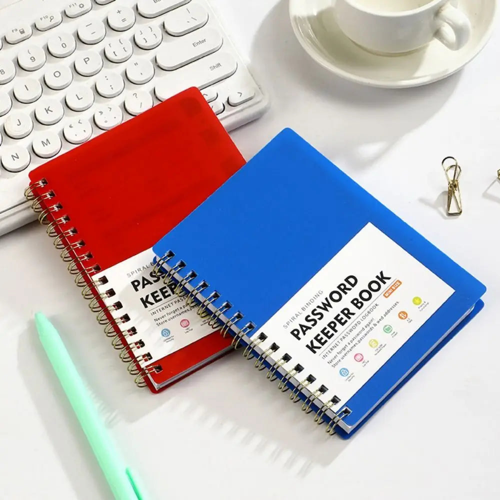 A blue spiral-bound password keeper notebook with red and white alphabetical tabs resting on a white surface.