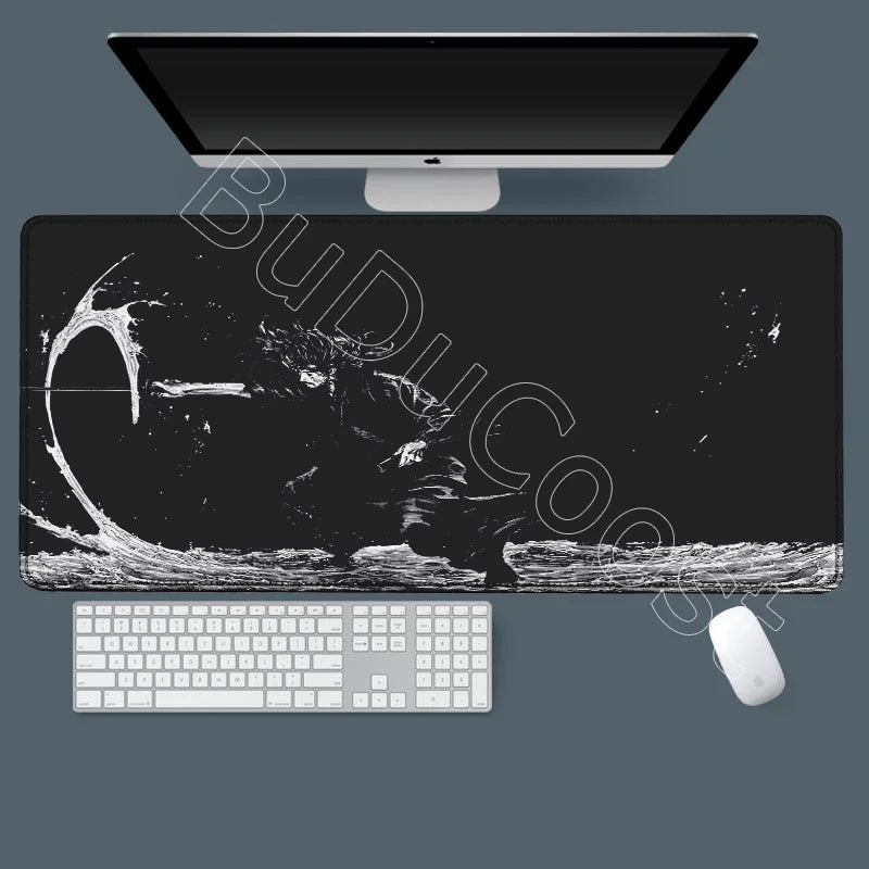 A black gaming mousepad with a white keyboard and white mouse placed beneath a computer monitor.