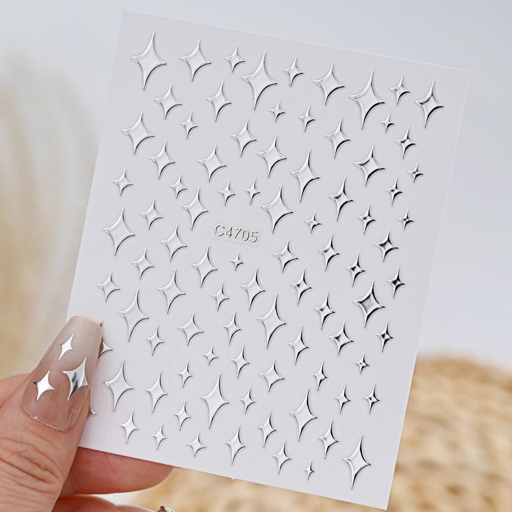 A hand holds a sheet of metallic 3D star nail art stickers for decoration.