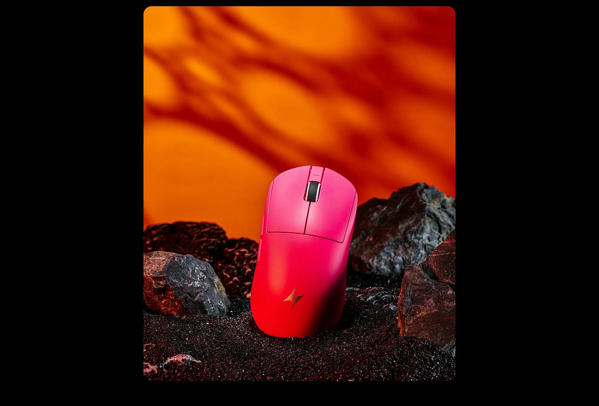 Pinke ergonomische kabellose Gaming-Maus liegt auf dunklen Felsen mit orangefarbenem Lichthintergrund.