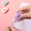 Eine Hand hält ein lila ausziehbar-Mini-Brieföffnerwerkzeug gegen ein rosa Stück Papier, mit zwei ähnlichen Werkzeugen sichtb