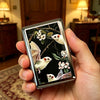 A hand holds a vintage stainless steel card and cash case featuring wildlife illustrations.