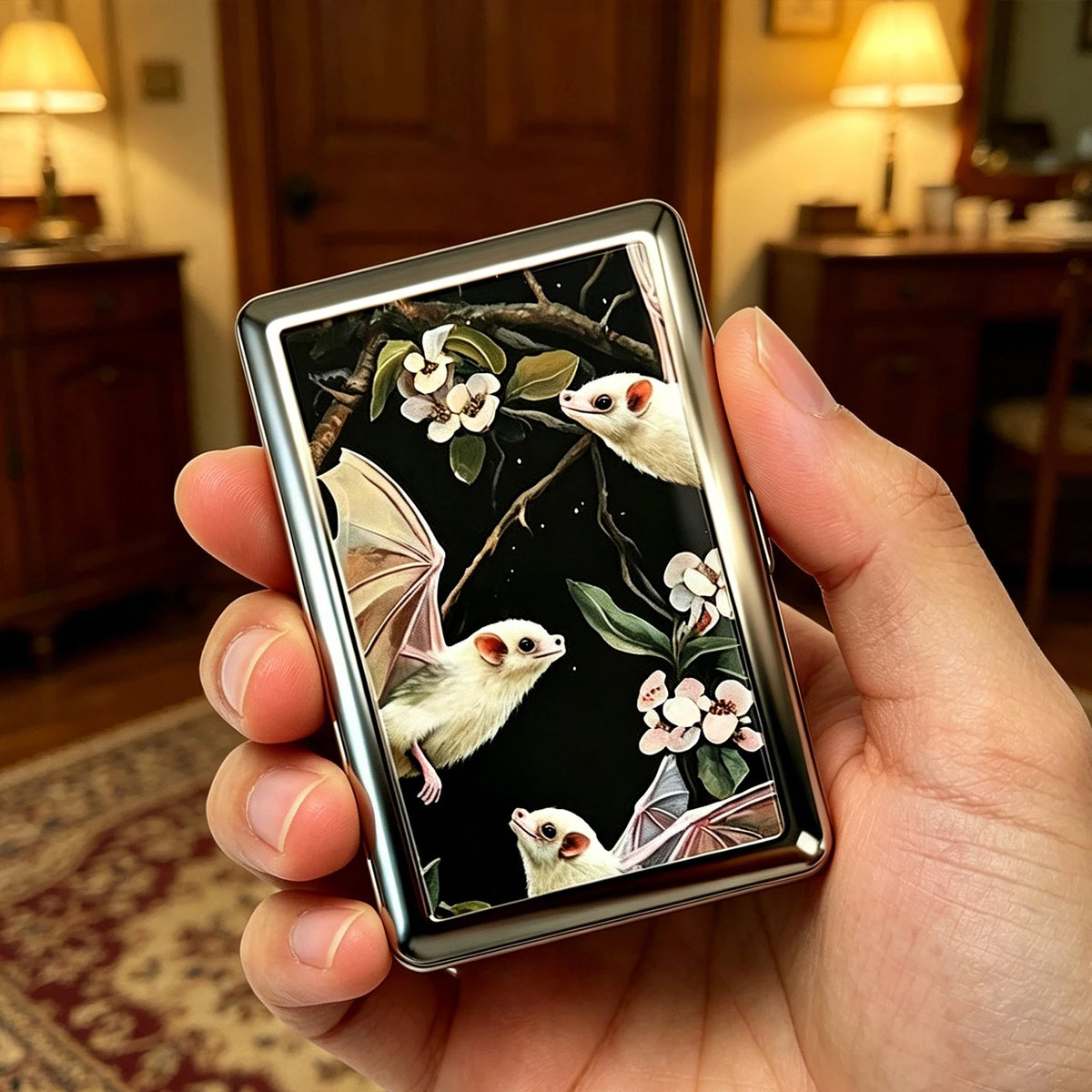 A hand holds a vintage stainless steel card and cash case featuring wildlife illustrations.