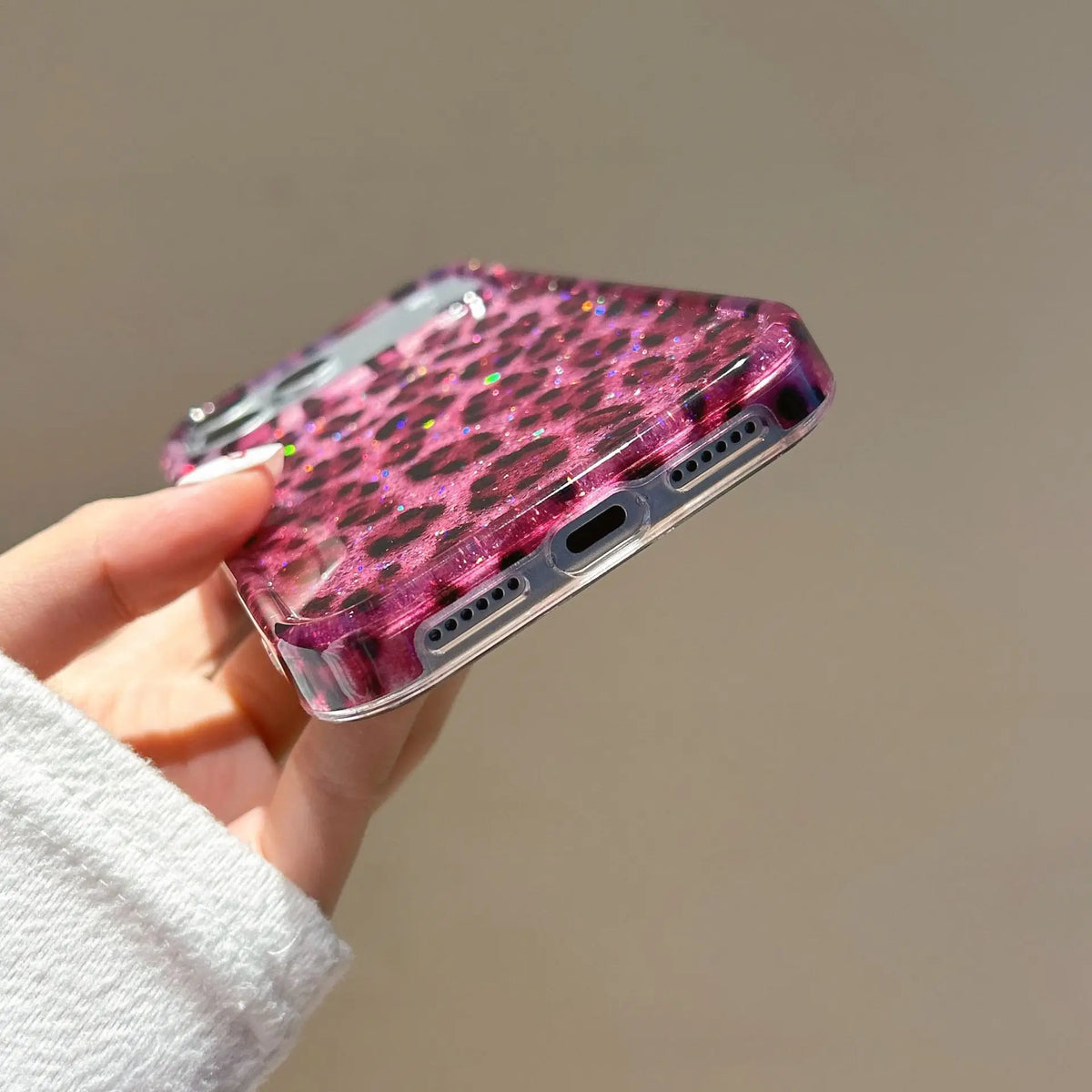 A hand holds a glamorous leopard print sequin shockproof phone case for an iPhone.