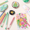 A collection of multi-color acrylic painting gel pens and related craft items arranged on a light background.
