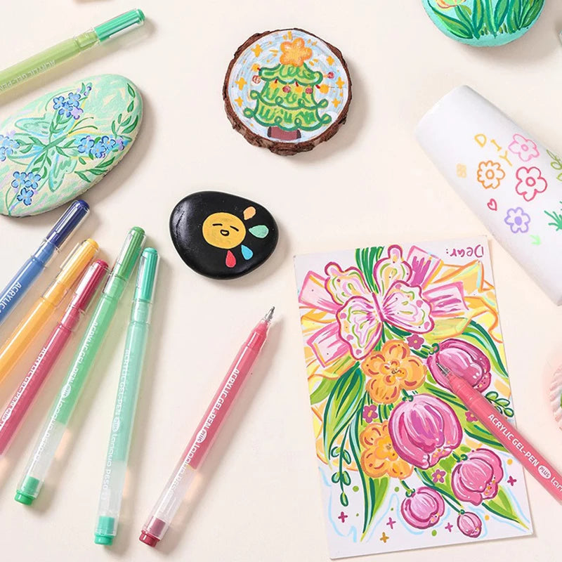 A collection of multi-color acrylic painting gel pens and related craft items arranged on a light background.