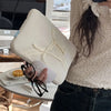 A person holds a beige laptop sleeve case, black glasses, and a laptop on a desk.